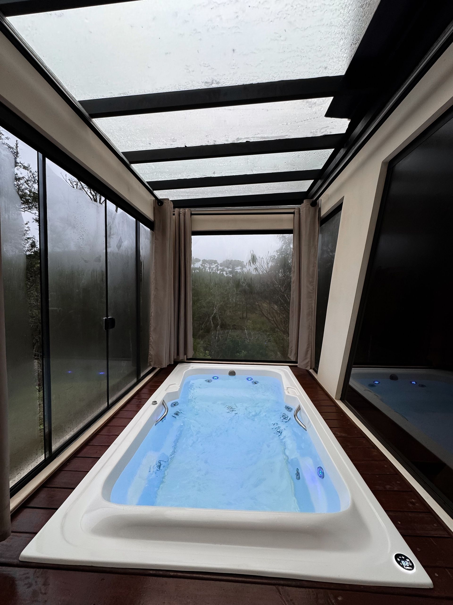 Modern indoor hot tub with glass ceiling and scenic outdoor view, perfect for relaxation.