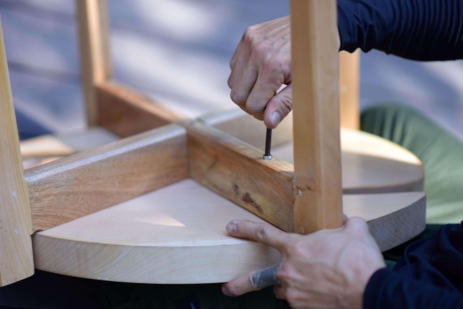 Hands assembling a wooden stool, highlighting craftsmanship and DIY spirit.